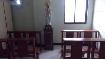 A room with wooden benches and a statue of a religious figure.