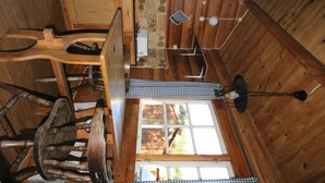 A wooden cabin interior with a wooden chair, a small table, a window, and a ceiling fan. - Saltdal Turistsenter - Campground (Saltdal)