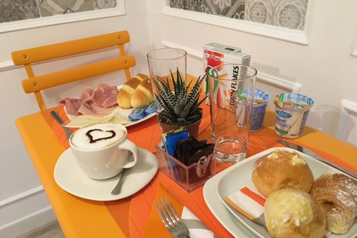 Una mesa de desayuno con una taza de café, pasteles y una pequeña planta.