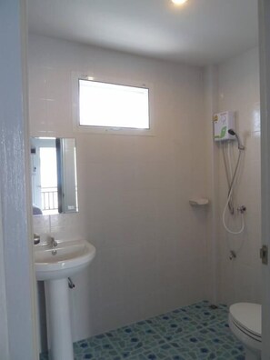 A small bathroom with a sink, toilet, and shower.