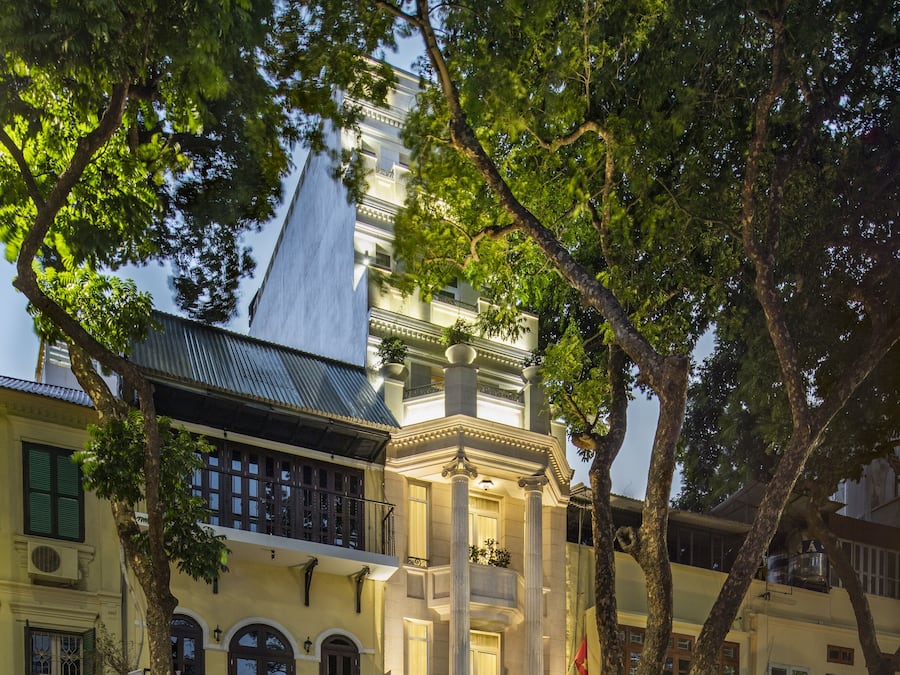 Um edifício histórico com uma varanda imponente, um café e uma placa com 'Silk Boutique'.
