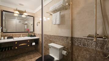Un baño con lavamanos de mármol, inodoro, cabina de ducha de vidrio y tocador con espejo.