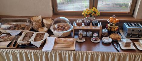 Un buffet de petit-déjeuner proposant un assortiment de pains, de viennoiseries, de fruits et de condiments.