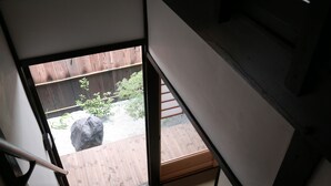 A staircase leading to an outdoor area with a wooden deck and a rock. - Kyomachiya-Oyado Hana (Kyoto)