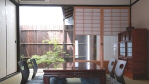 A traditional Japanese room with tatami flooring, a low wooden table, and shoji screens. - Kyomachiya-Oyado Hana (Kyoto)