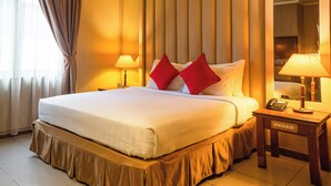 Habitación de hotel con una cama grande, dos lámparas de noche, una mesita con teléfono y un espejo grande en la pared.