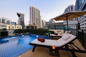 A rooftop pool area with lounge chairs and a poolside umbrella. - Syama Suite Sukhumvit 20 (Bangkok)