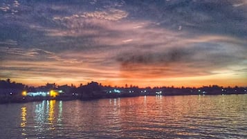 Atardecer sobre un cuerpo de agua con luces de la ciudad reflejándose en la superficie.