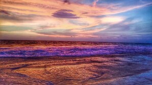 Uma praia com ondas e um céu ao pôr do sol.