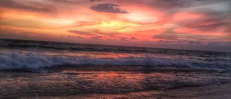 A beach with waves and a sunset.