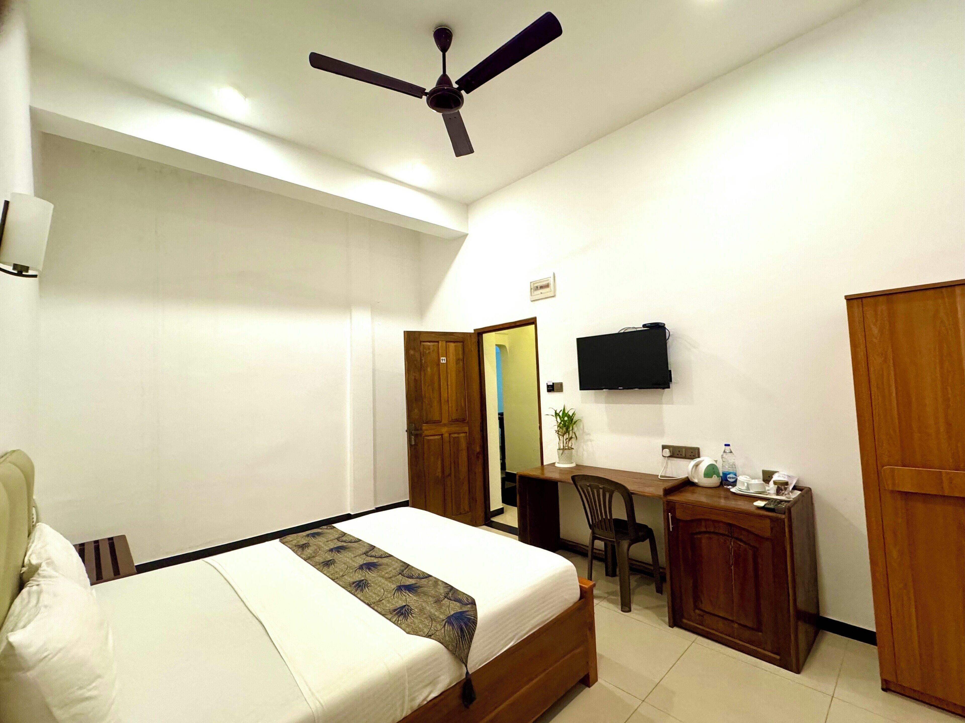 A hotel room with a bed, a desk, a chair, a television, and a wardrobe.