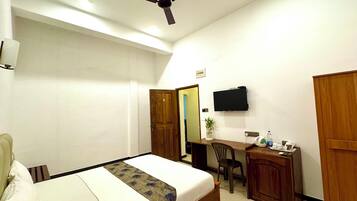Une chambre d’hôtel comprenant un lit, un bureau, une chaise, une télévision et une armoire.