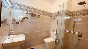 A bathroom with a glass shower enclosure, a toilet, a sink, and a towel rack. - Ziegler Cottage (Negombo)