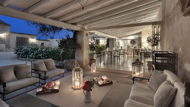 Un espace extérieur aménagé avec des canapés, une table décorée de bougies et des lanternes.