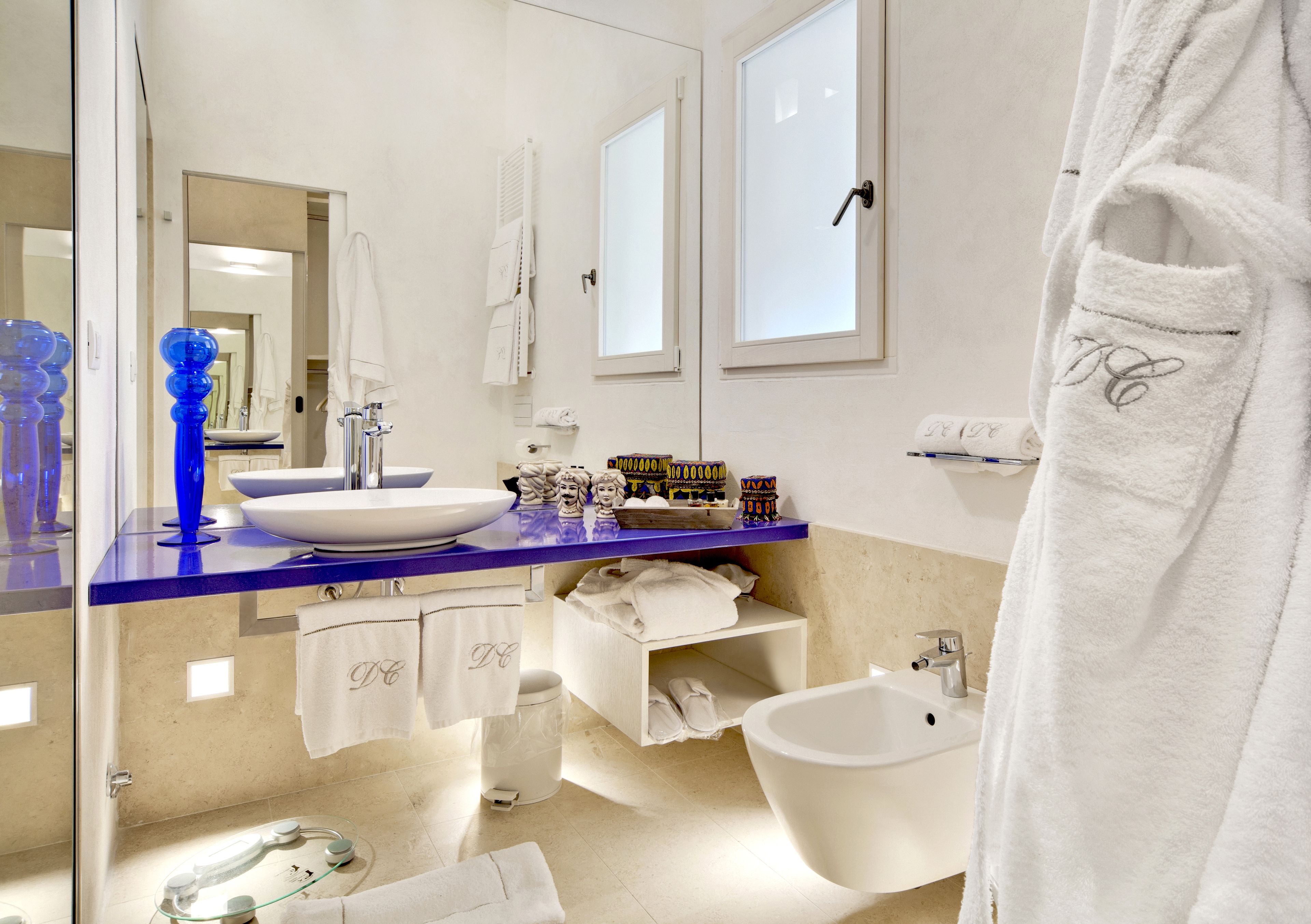 Un baño moderno con un lavabo blanco, una encimera azul y una bañera blanca.
