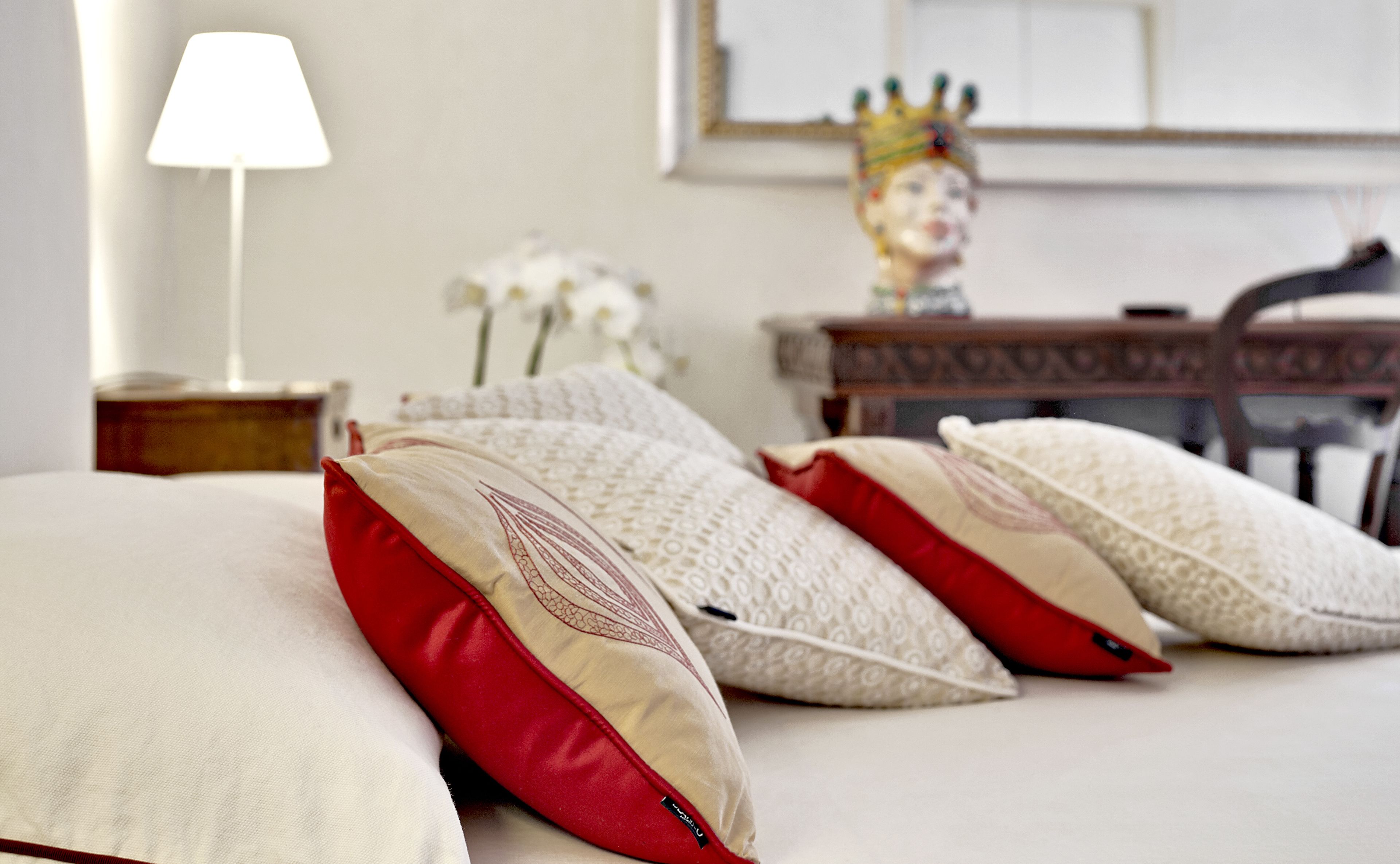 A neatly made bed with several pillows, a lamp, and a decorative item on a nightstand.