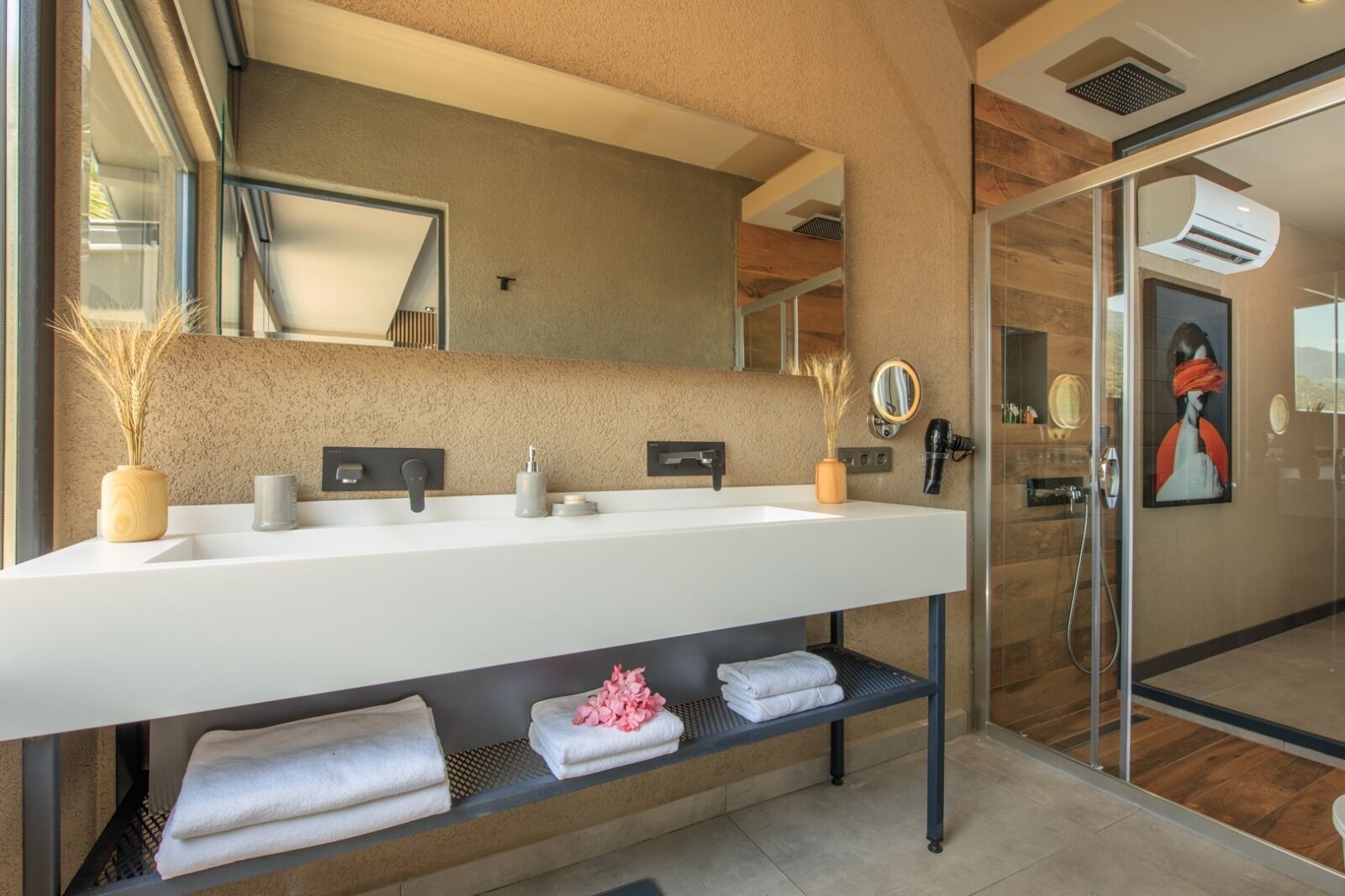 A modern bathroom with a large white sink, a mirror, and a glass shower enclosure.