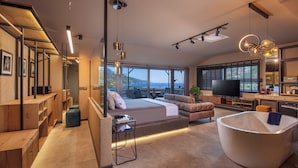 Una sala de estar moderna con un ventanal grande, un sofá, una mesa de centro y una bañera original.
