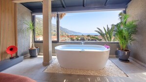 Un baño moderno con una bañera independiente, ventanas amplias y plantas en macetas.