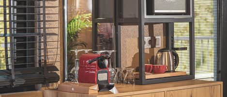 Una encimera de cocina con una cafetera, un electrodoméstico rojo y una jarra de café.
