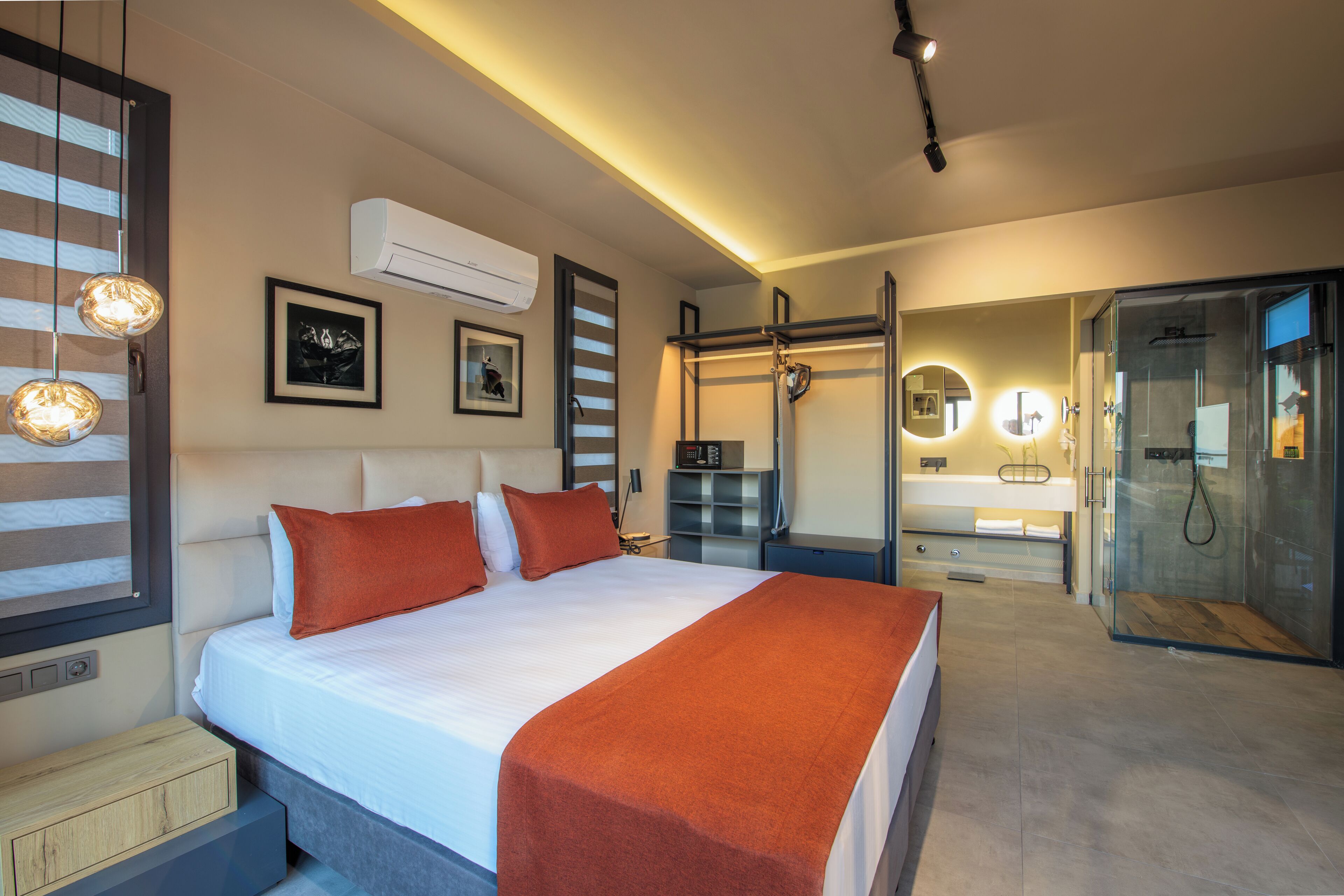 A modern hotel room with a large bed, a glass shower enclosure, and a bedside table.