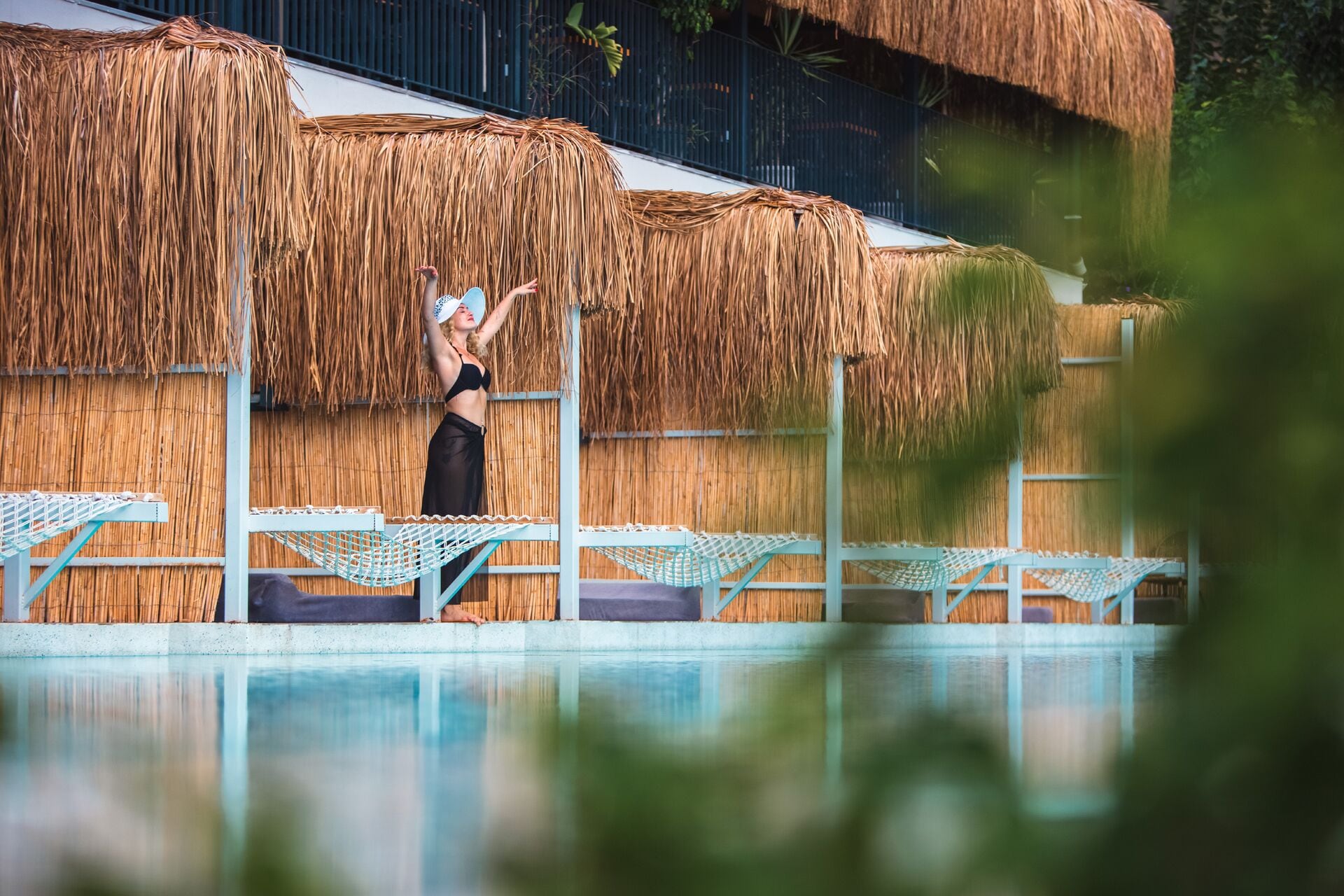 Un espace piscine doté de toits de chaume et de chaises longues.