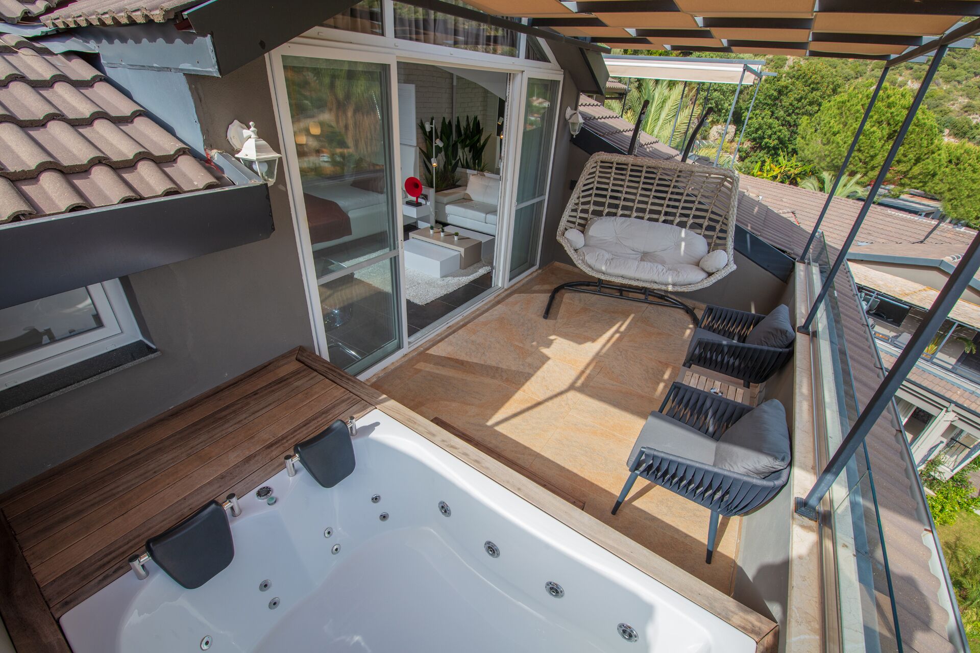 A rooftop terrace with a hot tub, outdoor seating, and a glass door leading to an indoor area.