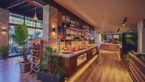 Un restaurante moderno con una barra larga, estanterías de madera y plantas en macetas.