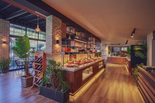 Een modern restaurant met een lange toonbank, houten planken en plantenbakken.