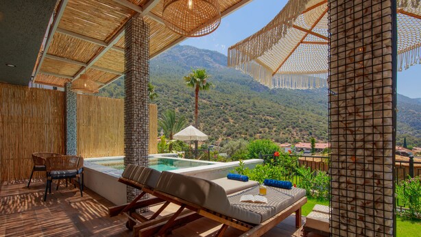 Un área de descanso al aire libre con muebles de madera, una piscina y vistas a un paisaje montañoso.