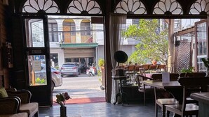 A cozy cafe with wooden furniture, a small table with a vase and books, and a view of the street outside. - Rustic River Boutique (Chiang Mai)