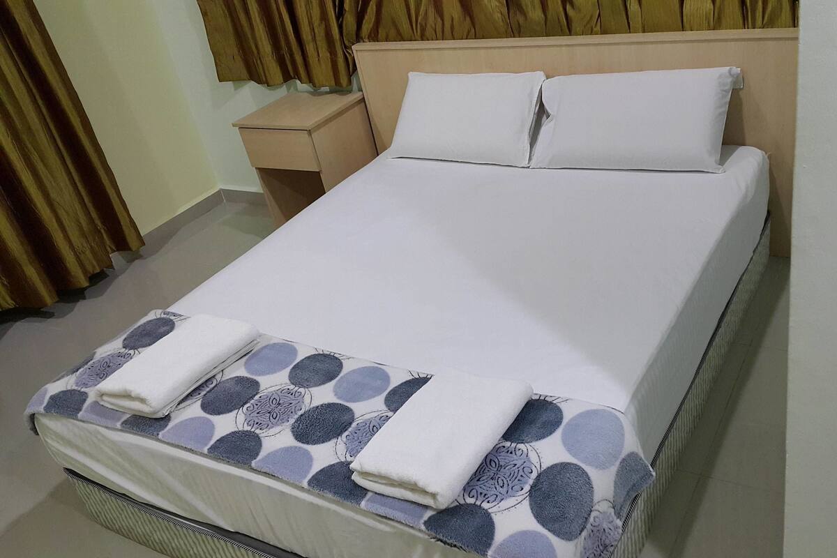 A neatly made bed with a patterned bedspread and two pillows.