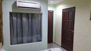 A room with a window covered by sheer curtains, a wall-mounted air conditioner, and a closed wooden door. - First and New Star Hotel (Kuala Lumpur)