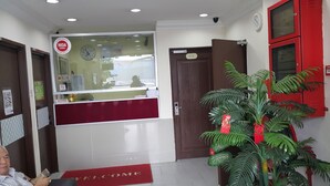 A reception area with a clock, a red welcome mat, and a potted plant. - First and New Star Hotel (Kuala Lumpur)