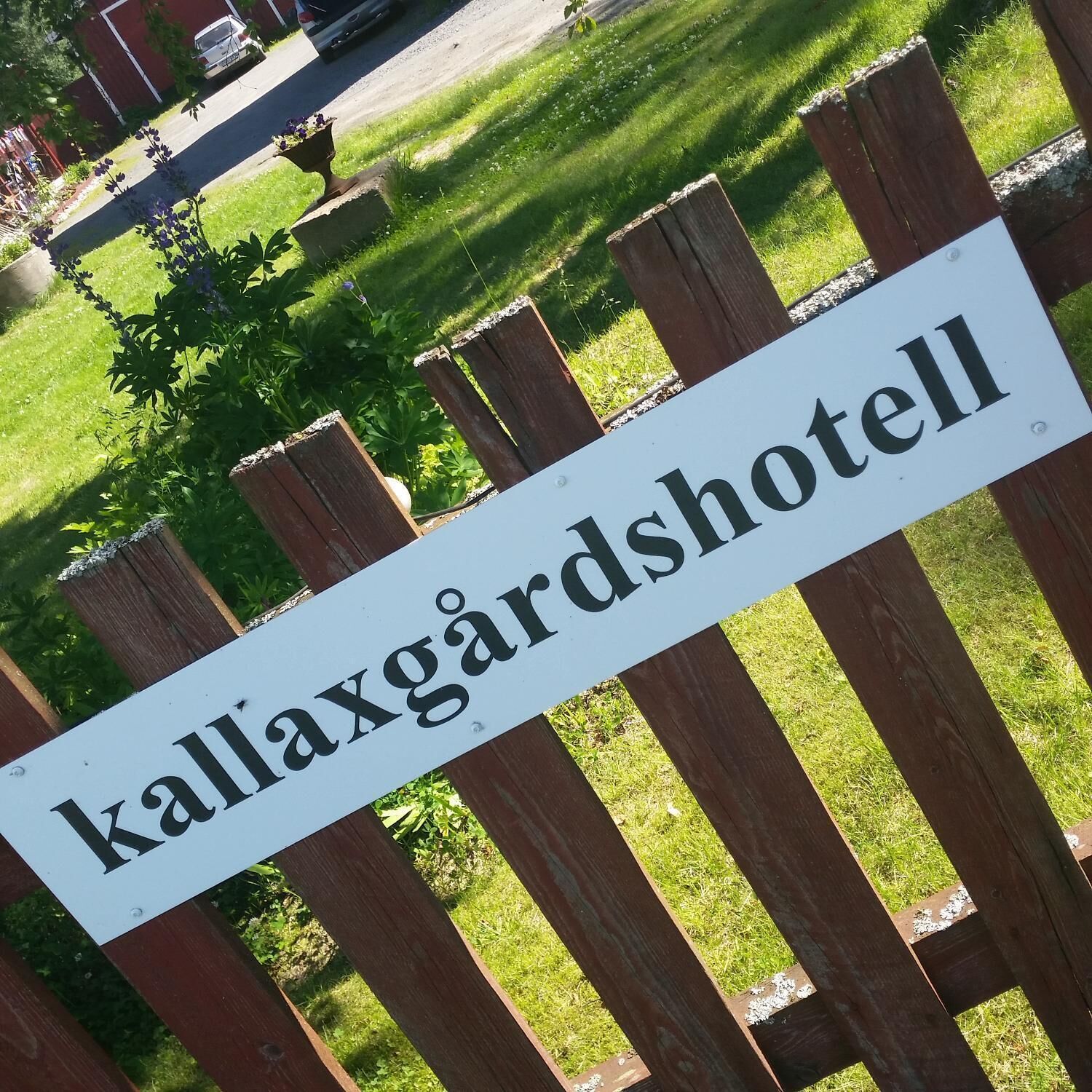En skylt med texten ”Kallaxgärdshotell” på ett trästaket.