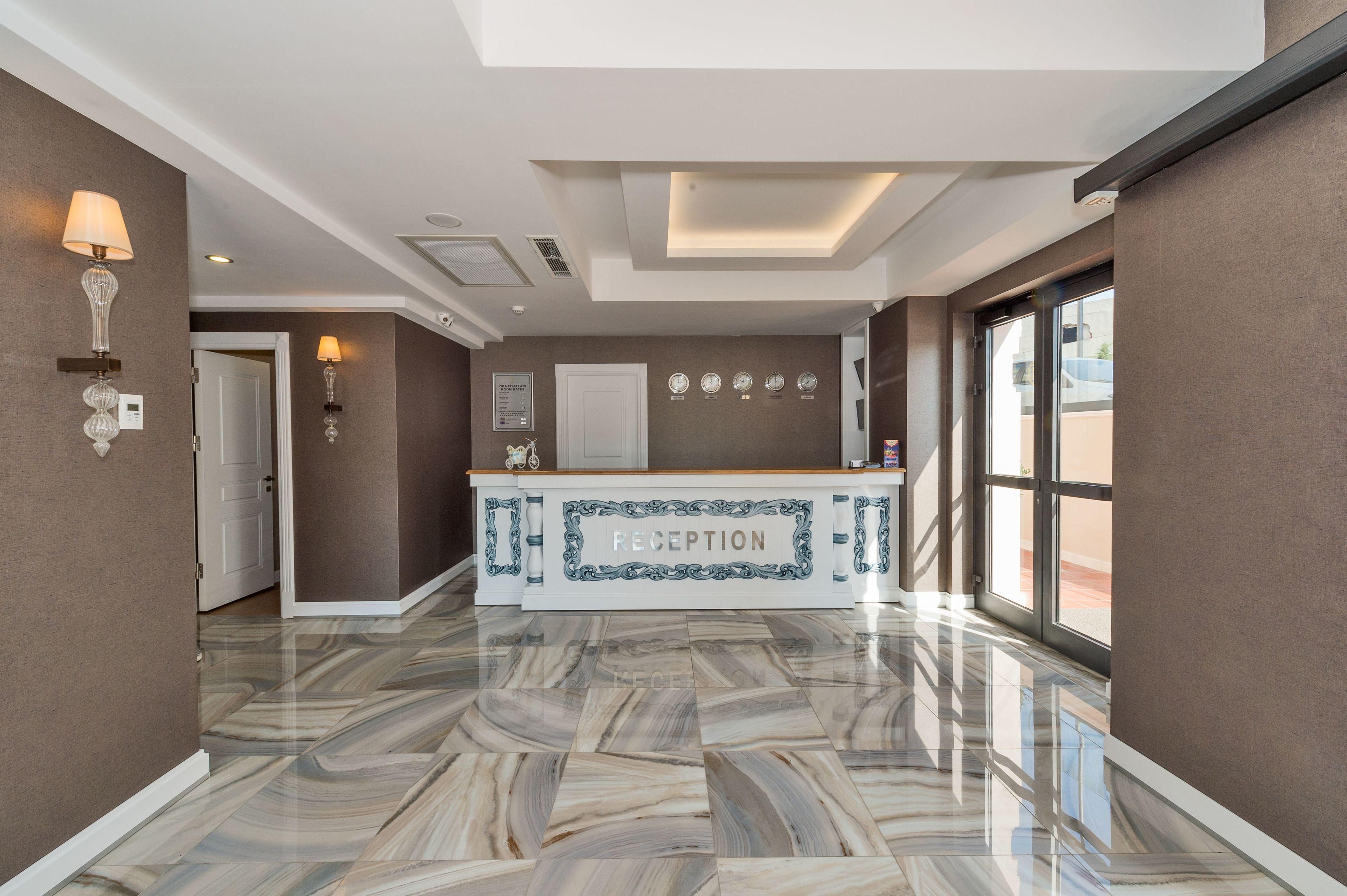 A reception area with a marble floor, a reception desk, wall-mounted clocks, and a door leading to another room.