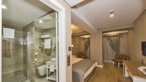 A hotel room with a glass shower enclosure, a bed, a desk, and a chair. - Hanna Hotel (Istanbul)