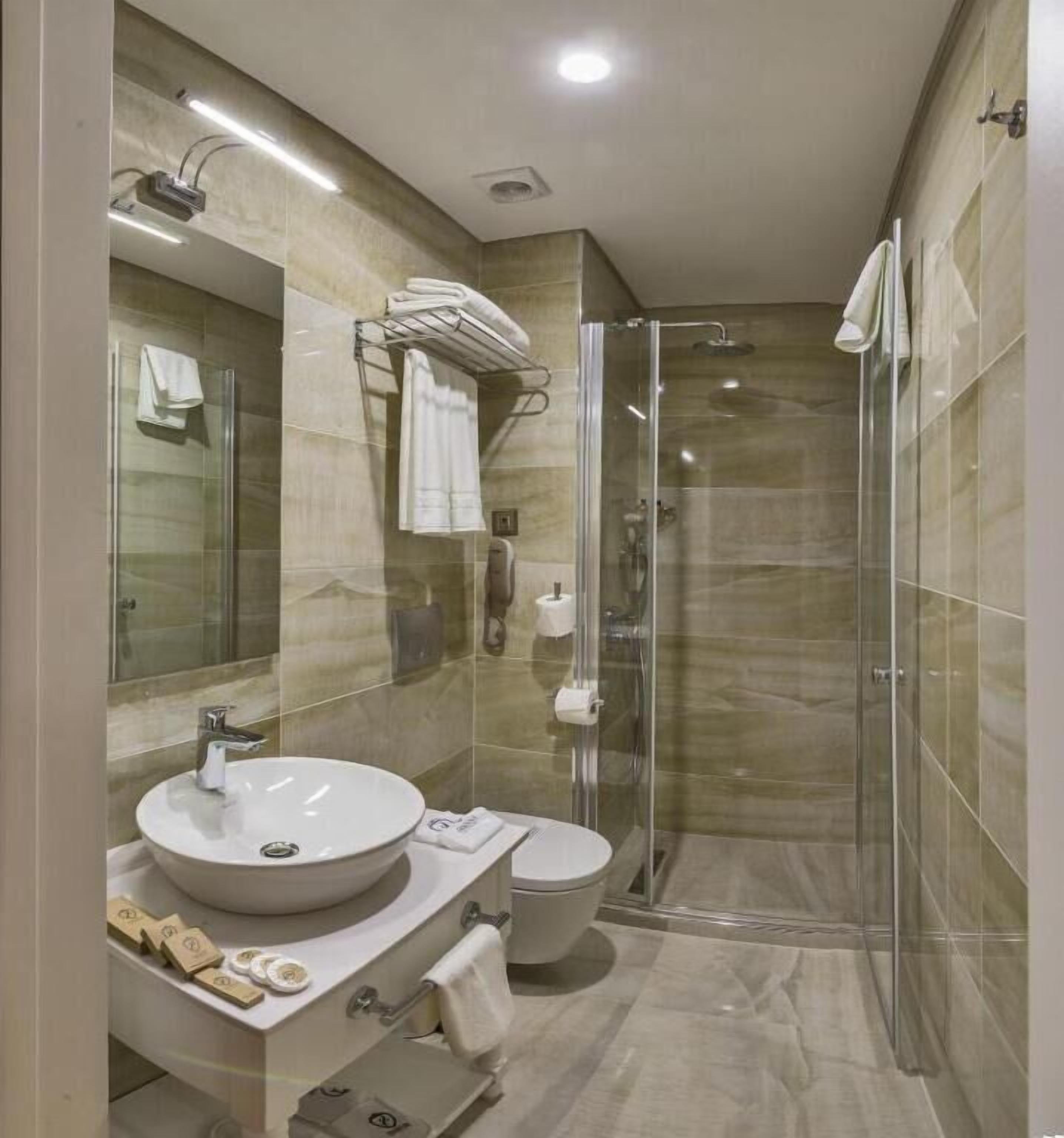 A modern bathroom with a glass-enclosed shower, a sink with a mirror, and a toilet.