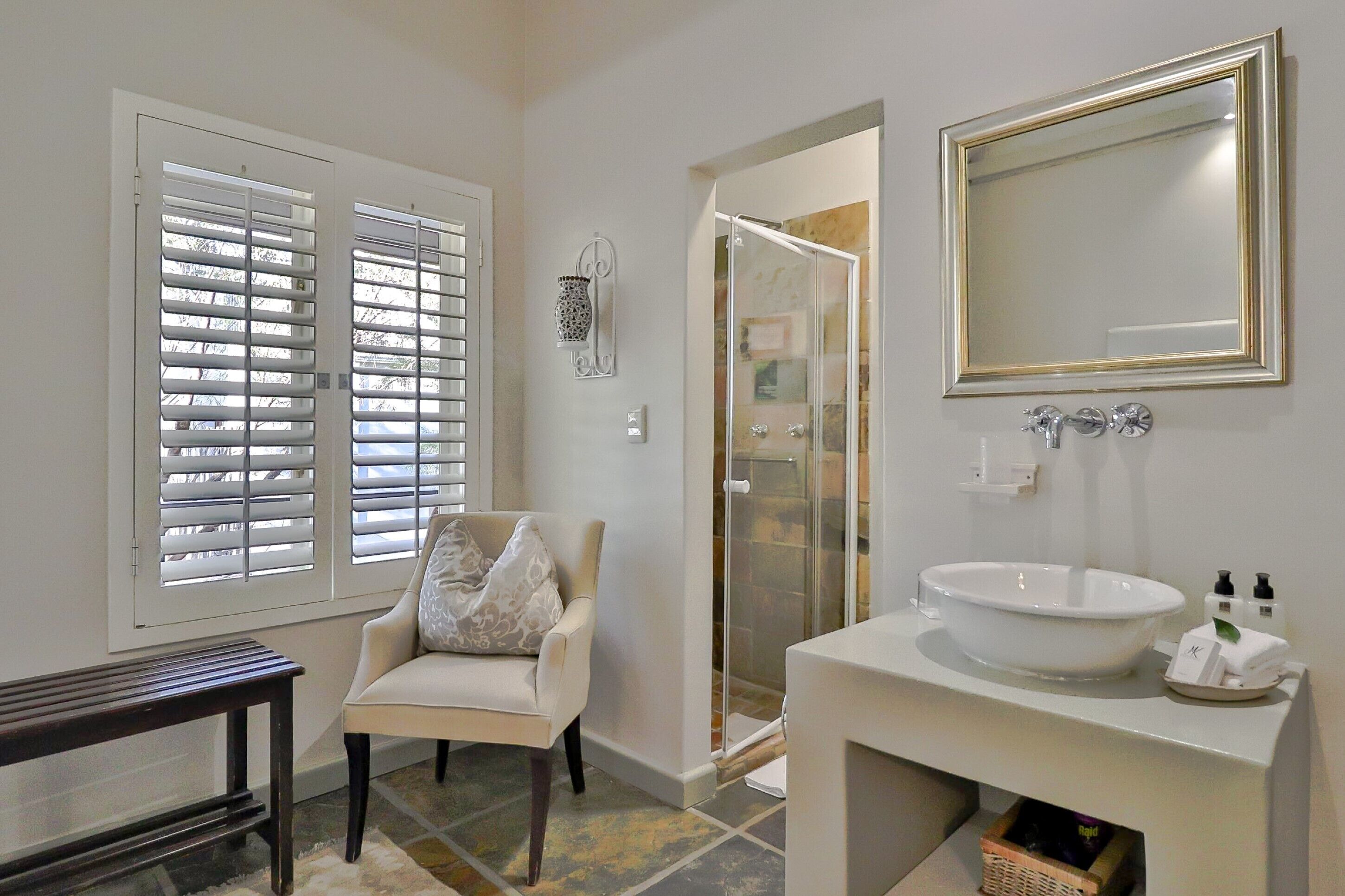 A bathroom with a white sink, a mirror, and a chair.