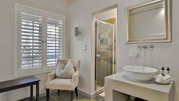 A bathroom with a white sink, a mirror, and a chair.