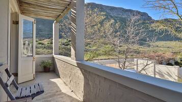 Enjoy breathtaking views of the surrounding mountains from this balcony, featuring a comfortable bench and lush greenery.