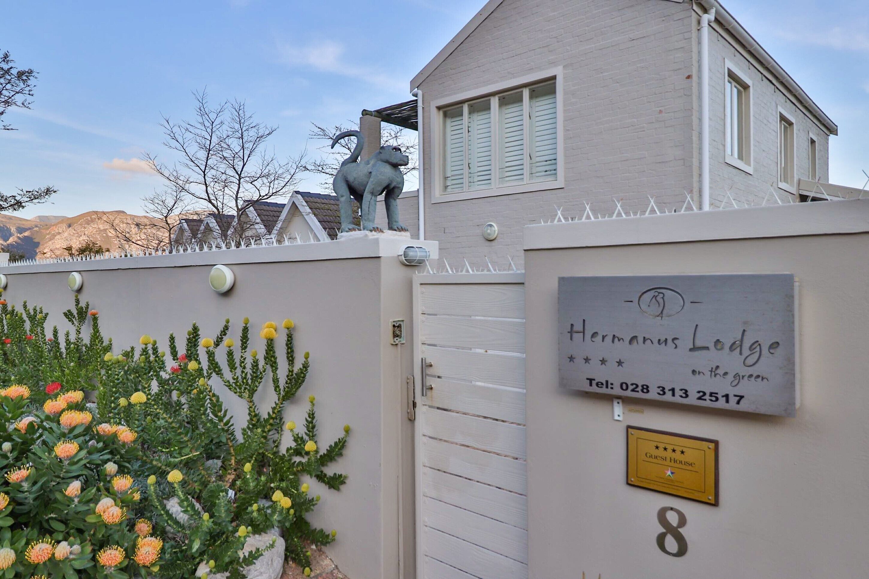 Casa de huéspedes llamada "Hermanus Lodge", con un número de contacto y un cartel que dice "Casa de Huéspedes".