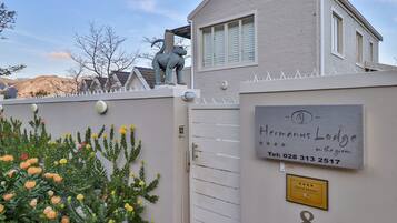 Casa de huéspedes llamada "Hermanus Lodge", con un número de contacto y un cartel que dice "Casa de Huéspedes".