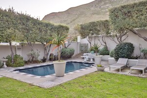 Ein Garten mit Swimmingpool, Liegestühlen und Topfpflanzen.