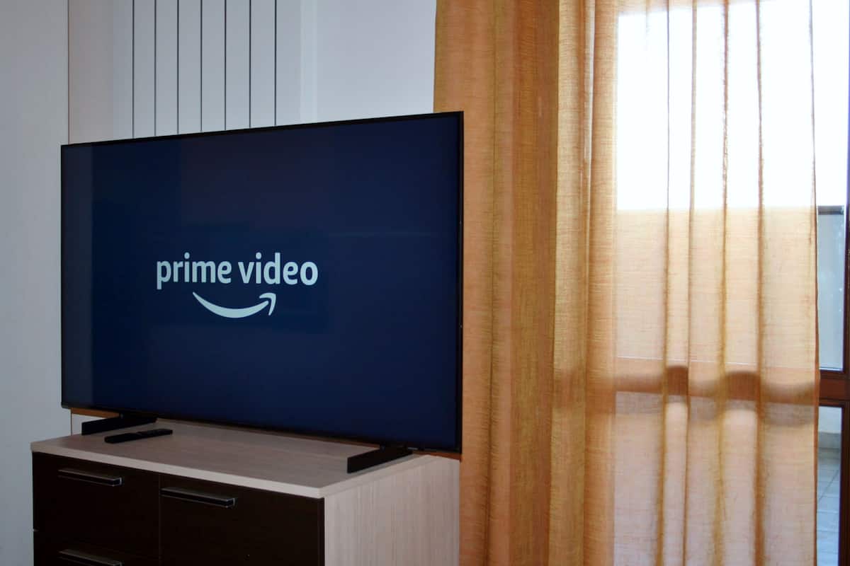 Television, jonka näytöllä näkyy Prime Videon logo, ja joka on sijoitettu puiseen kaappiin.