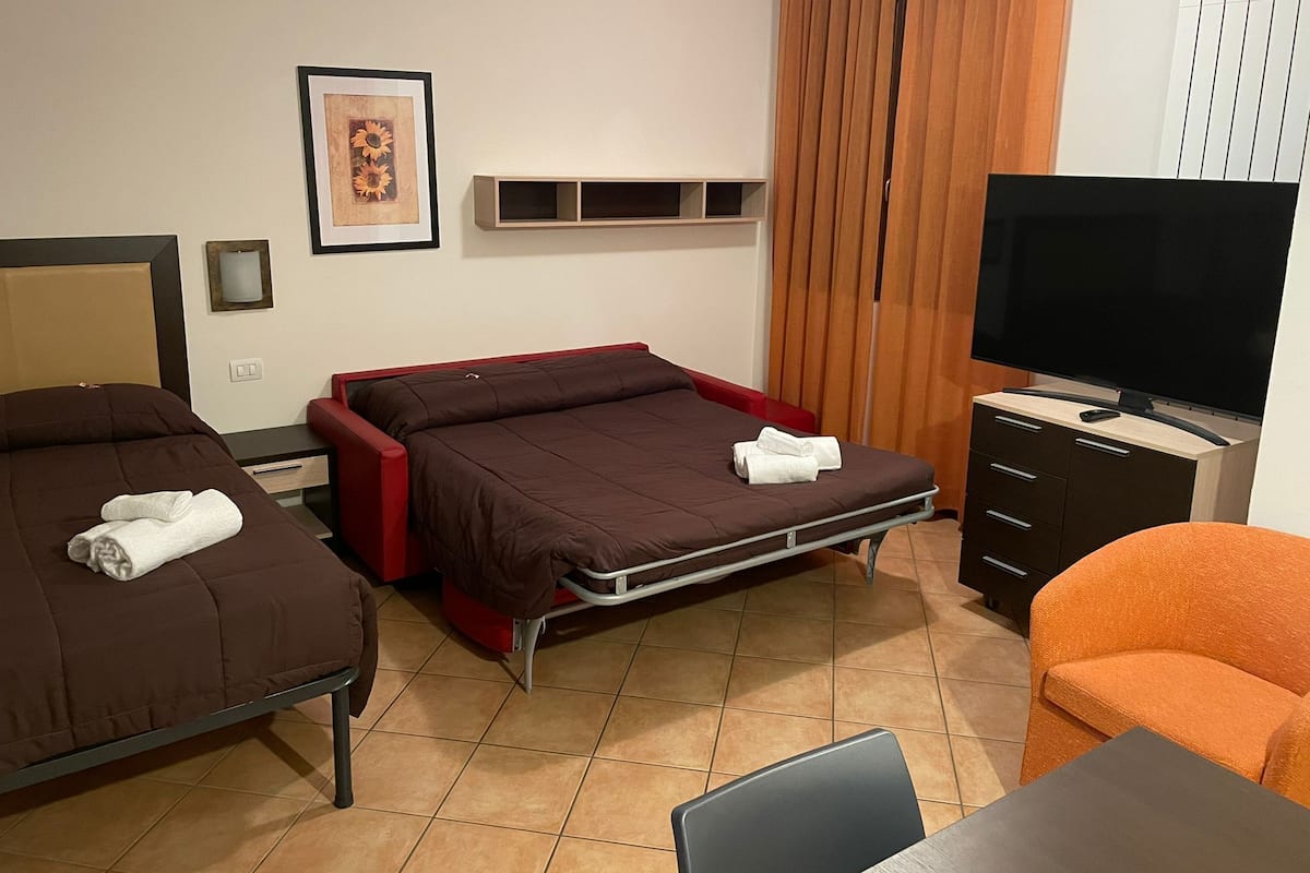 Hotellihuone, jossa on kaksi erillistä sänkyä, televisio, työpöytä ja tuoli.