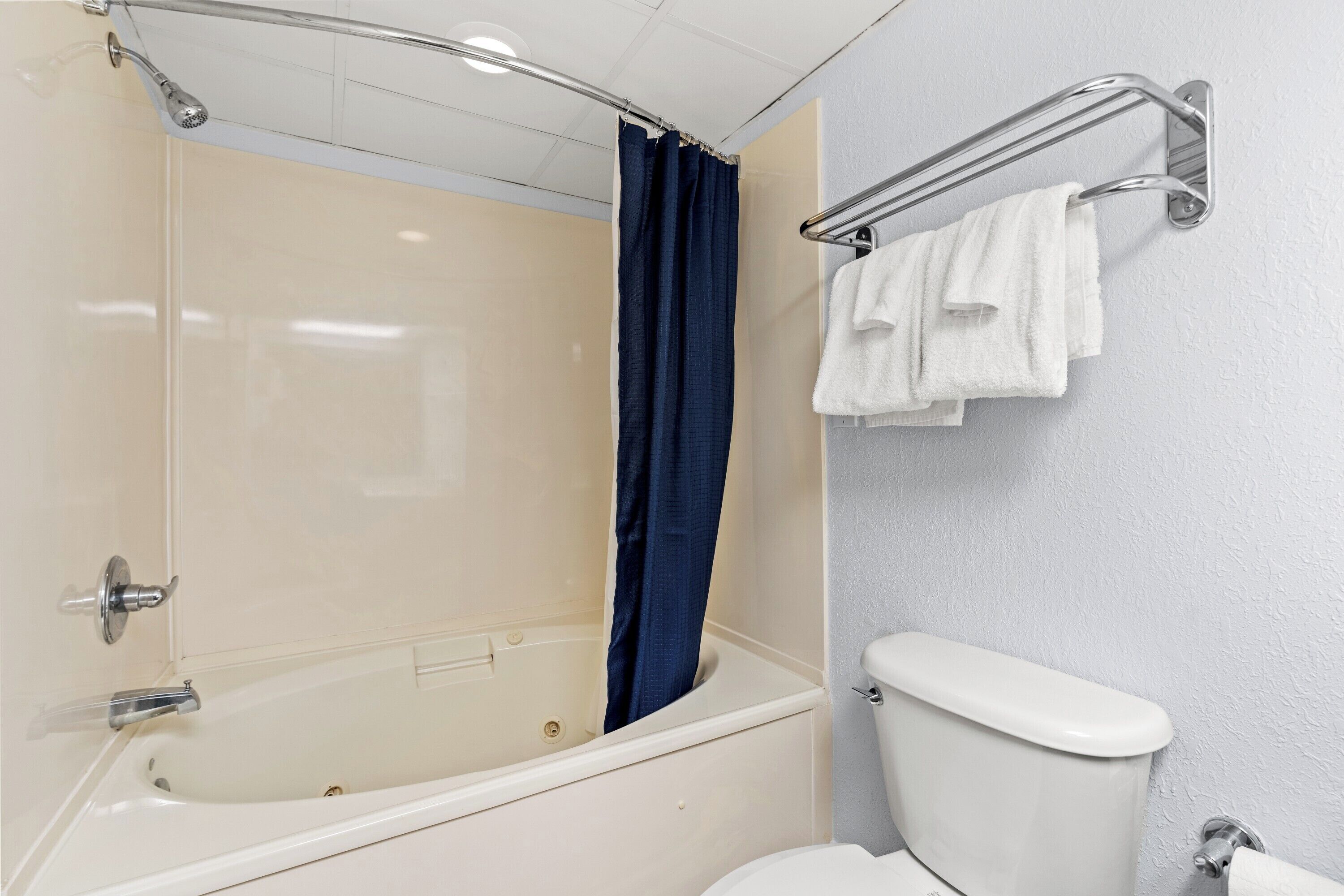 A bathroom with a bathtub, a shower, a toilet, and a towel rack.