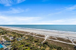 A beach with a clear sky, palm trees, and a sandy path leading to the water. - Boardwalk Beach Resort by Elliott Beach Rentals (Myrtle Beach)