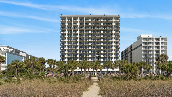 A multi-story hotel with a uniform exterior, numerous balconies, and a central entrance. - Boardwalk Beach Resort by Elliott Beach Rentals (Myrtle Beach)