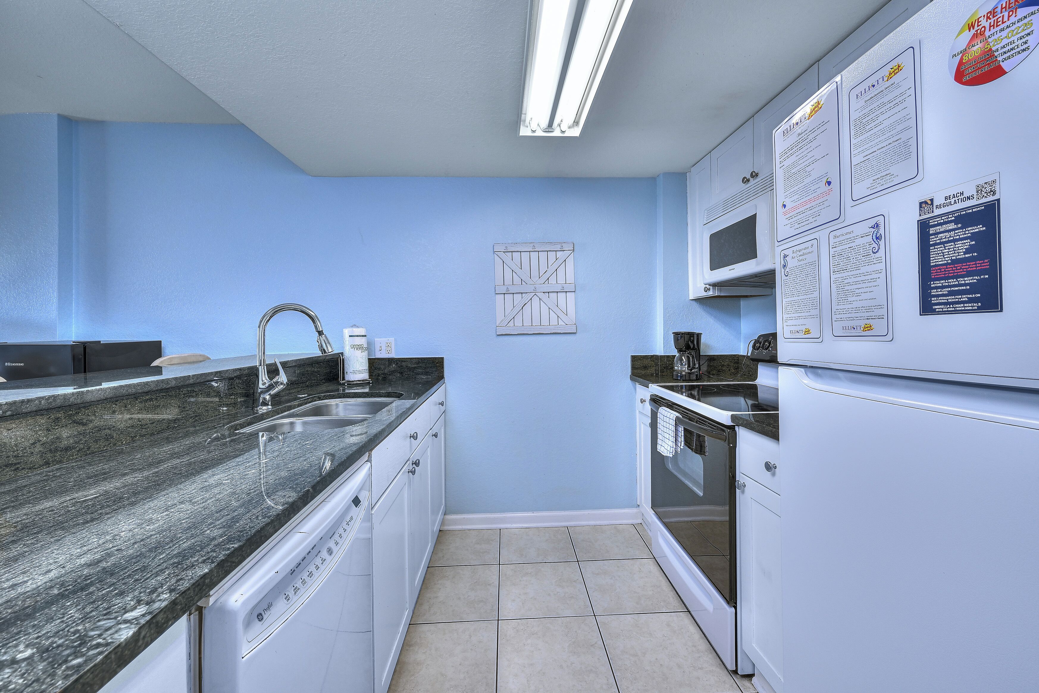 A compact kitchen with a granite countertop, white cabinets, and a dishwasher.